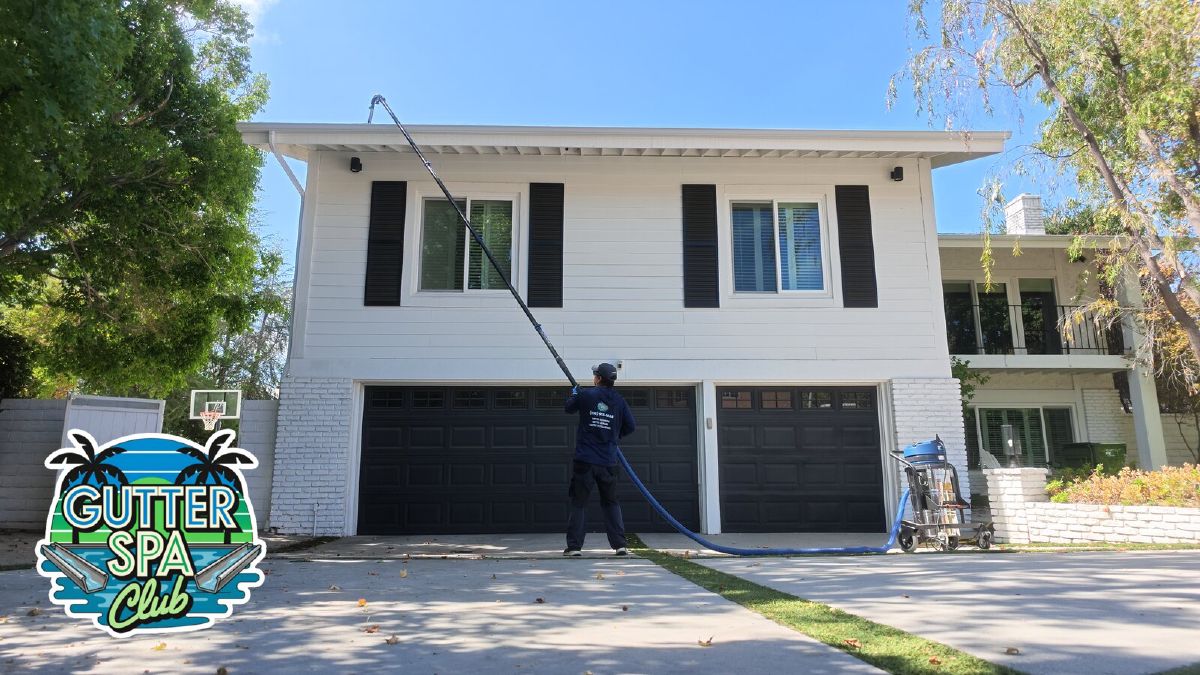 Ritchie cleaning a second-story gutter from the driveway with a pole-mounted gutter vacuum