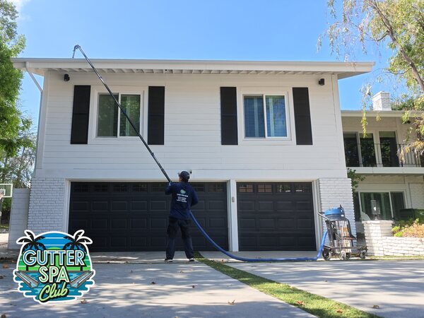 Ritchie of Gutter Spa Club cleaning a second-story gutter from the ground with a pole-mounted gutter vacuum