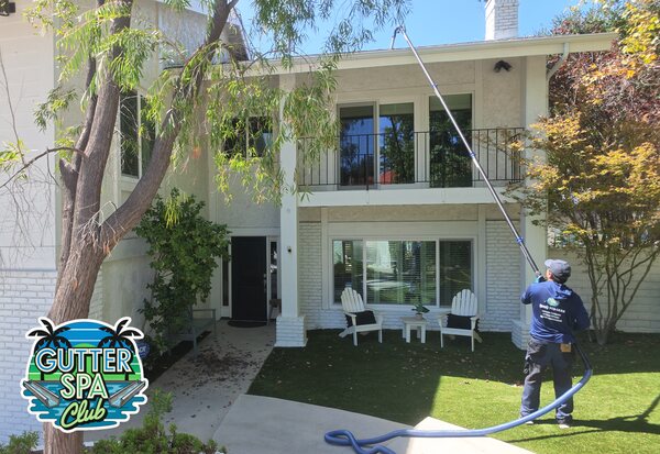 Ritchie cleaning a second-story gutter from the ground with a pole-mounted gutter vacuum